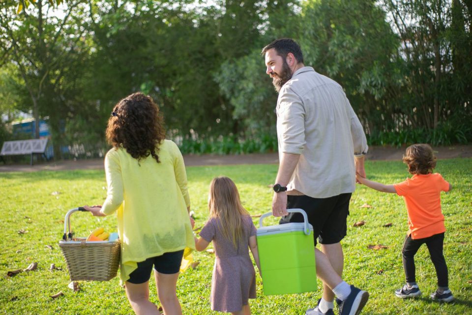A family of four enjoys a picnic in a sunny park, capturing a joyful day outdoors.